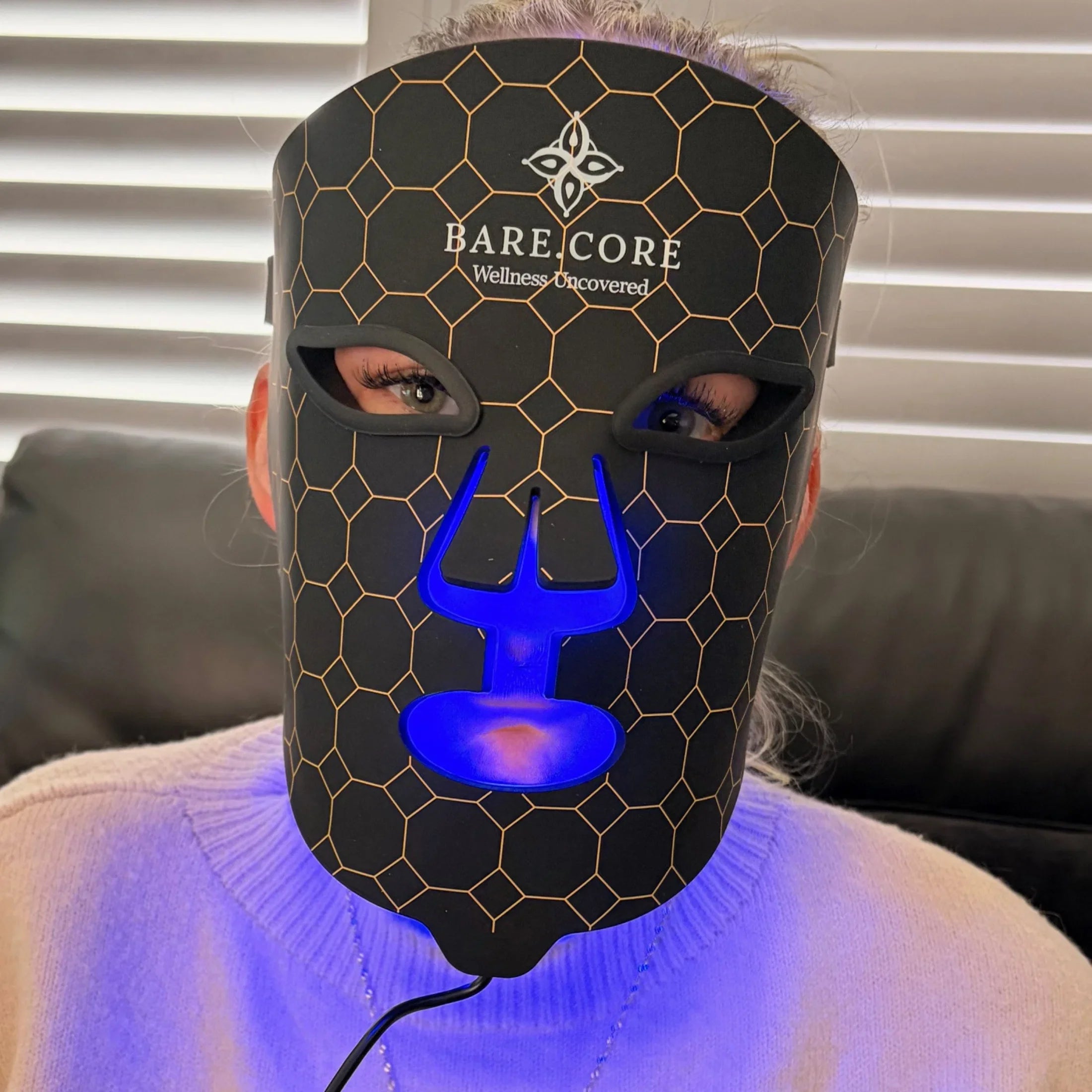 Person wearing LED light therapy mask with honeycomb design for skincare