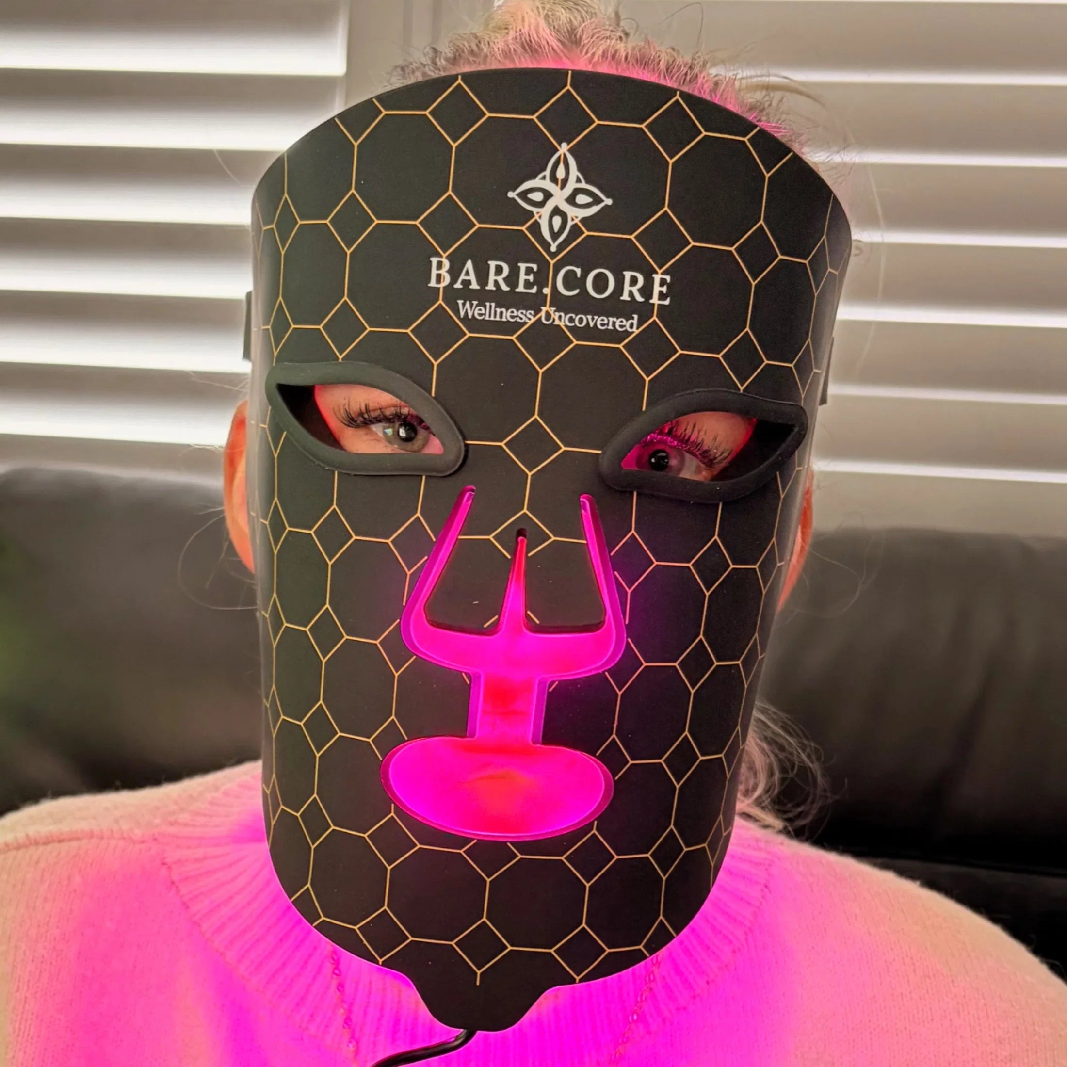 Person wearing LED light therapy mask with honeycomb pattern for skincare treatment